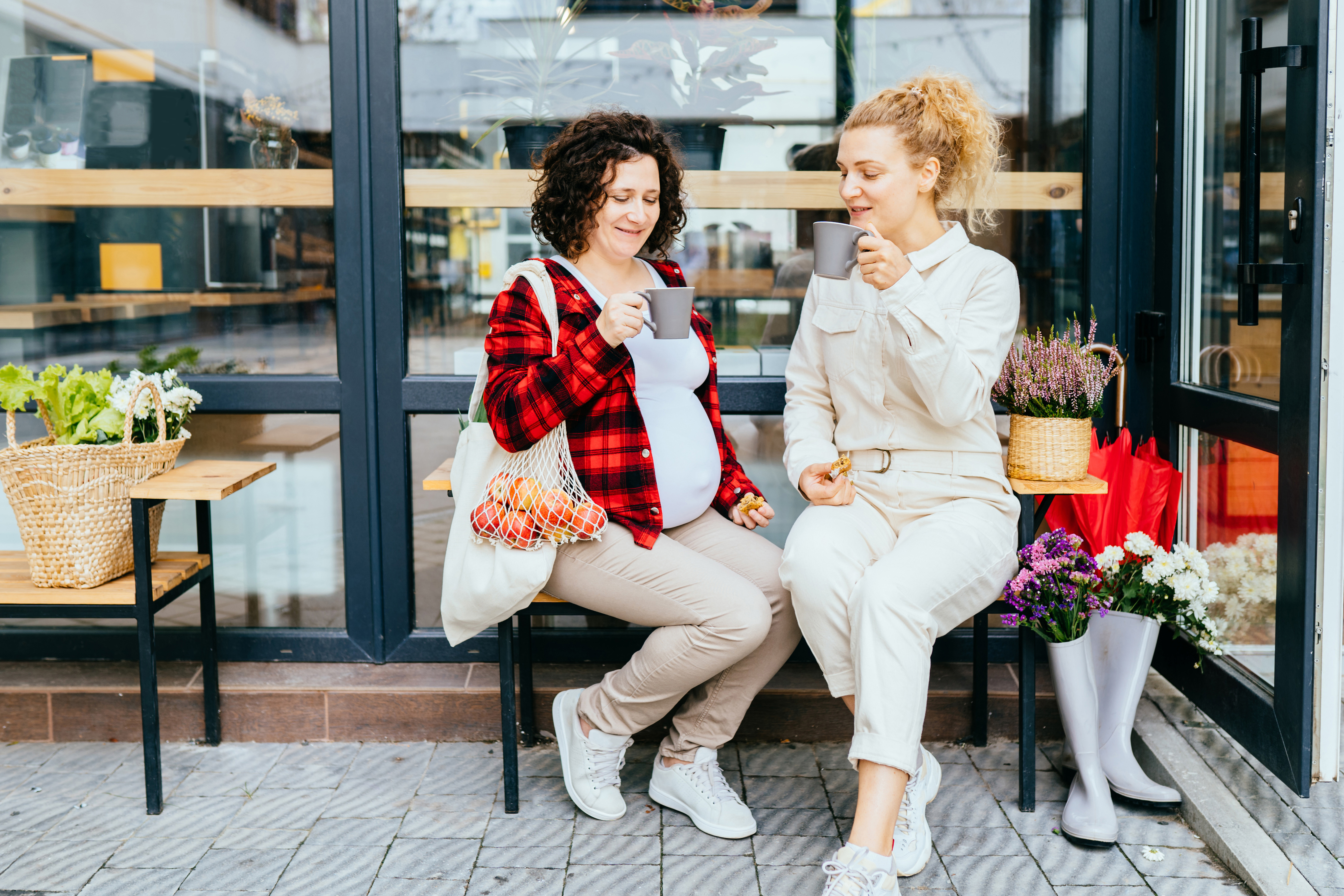 Full length portrait of cheerful female friends laughing during togetherness pastime after food shopping, happy women satisfied with sincerely friendship relations posing outdoor over grocery store.