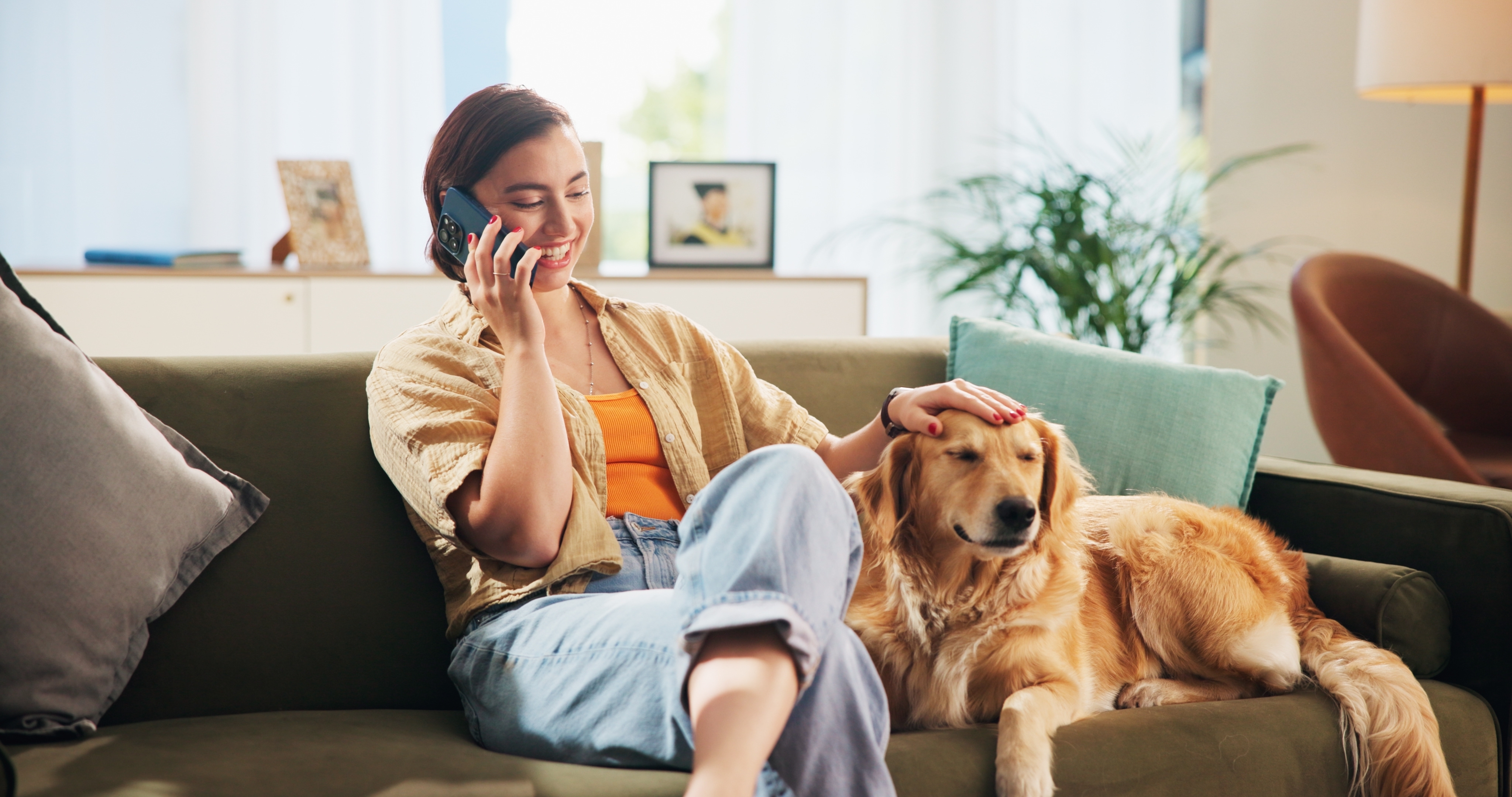 Happy, phone call and woman with dog on sofa for bonding, care and relax together in living room. Chill, pet and person with Golden Retriever on smartphone for chat, social networking and contact